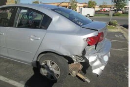 Silver sedan with rear-quarter collision damage, before repair