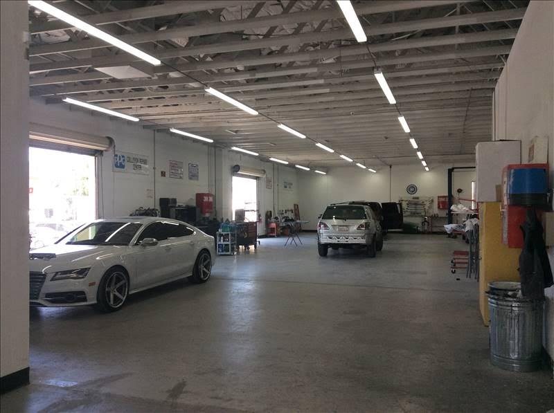 Bright indoor repair bay with a white Audi sedan